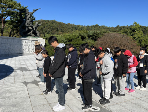 방과후아카데미 ‘짱스쿨프렌드’의 주말체험활동 ‘한강역사탐방’에 참여한 청소년들이 국립현충원 현충탑에서 묵념을 하고 있다