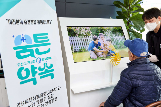 서초구 내 방배노인종합복지관에서 한 어르신이 ‘숨튼약속’ AI 인터랙티브 숨 건강 체험 장치를 통해 자신의 숨으로 ‘생명의 정원’을 완성하는 체험을 하고 있다
